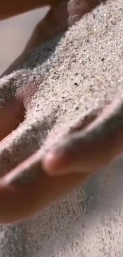 Mobile wallpaper showing a hand allowing sand to flow gently through fingers.