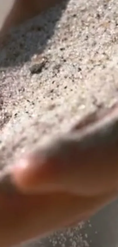 Close-up of sand flowing through a hand, creating a natural serene aesthetic.