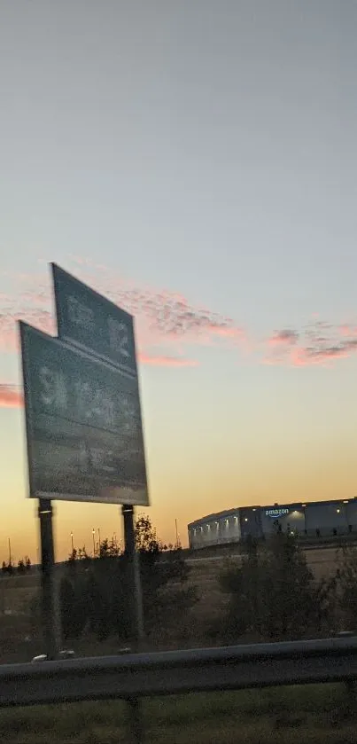 Highway at sunset with road signs against a warm amber sky.