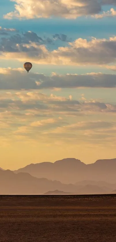 Hot air balloon over desert with mountains and clouds in a serene landscape.