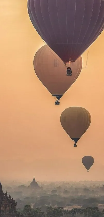 Hot air balloons float over an ancient landscape at sunset.