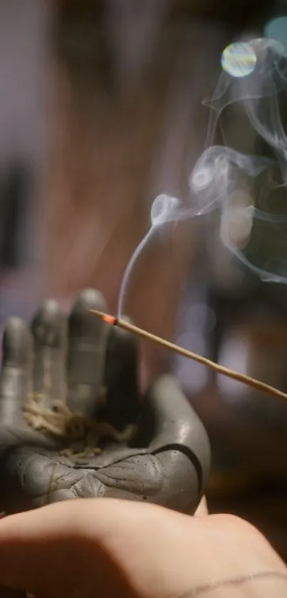 A hand sculpture holding burning incense creating a serene ambiance.