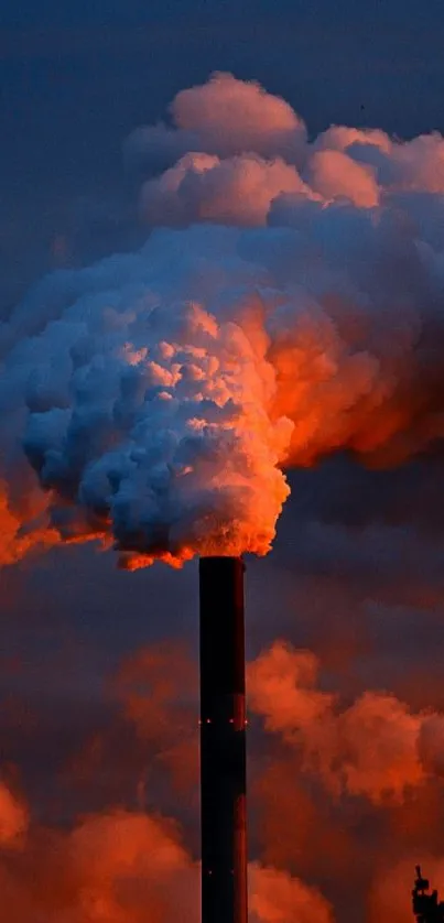 Chimneys emitting smoke at sunset against a dark sky.