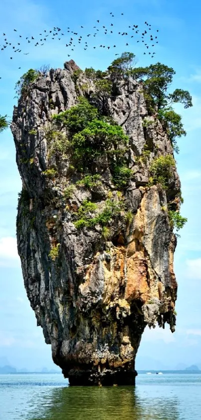 Towering island cliff with birds and blue sky.