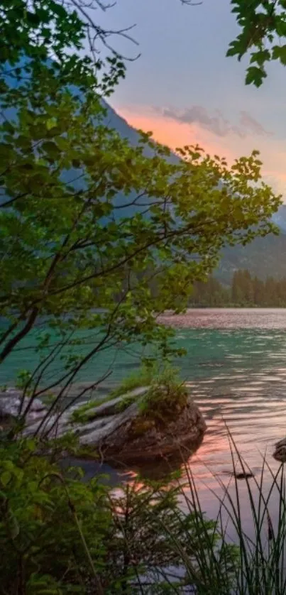 Peaceful lake at sunset with mountains and lush greenery.