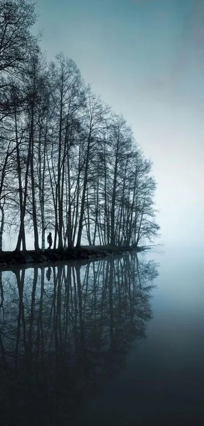 Serene blue lake with tree reflections in misty setting.