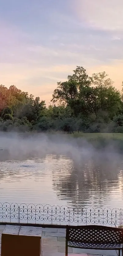 Misty lake at sunset with calm waters and trees in the background.