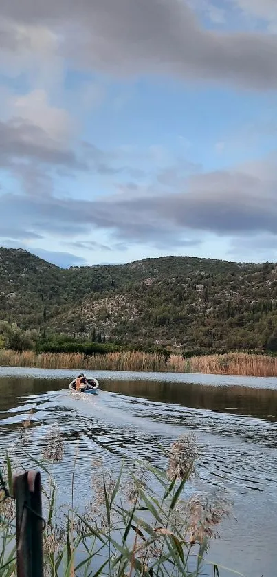 Tranquil lake with rolling hills and a cloudy sky.