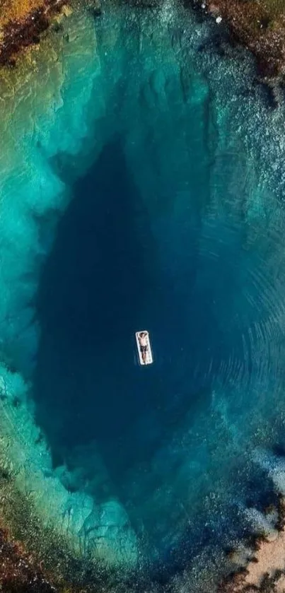 Aerial view of a peaceful teal lake with a single boat in the center.