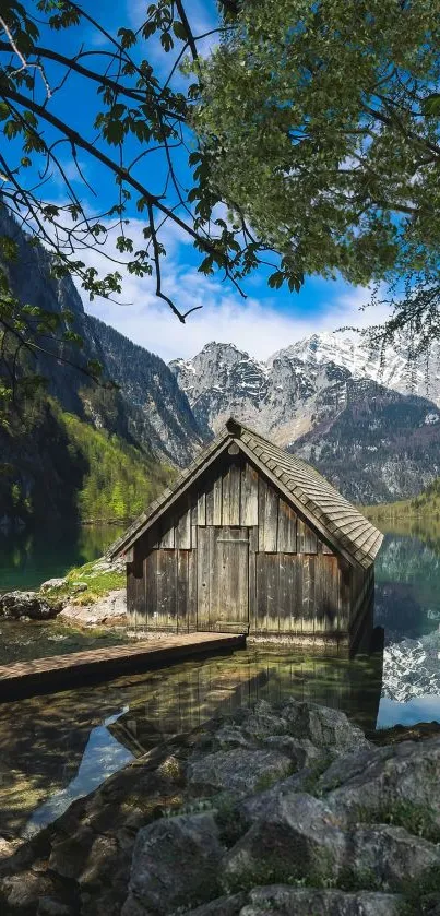 Lakeside cabin with mountains and blue sky, peaceful nature scene.