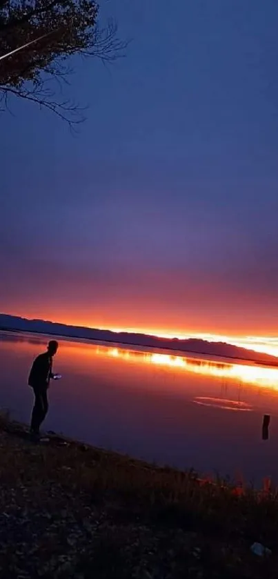 Silhouetted figure by a lake at sunset with vibrant sky colors.