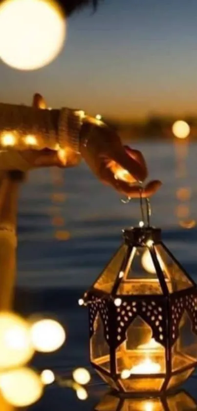 A hand holding lantern over water with glowing lights in dark blue night.