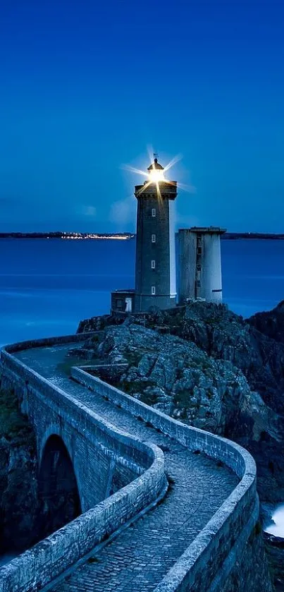 Lighthouse against a deep blue evening sky on rocky coastline.