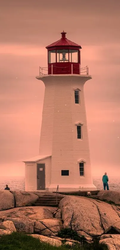 Lighthouse on rocky coast under warm, hazy sky.