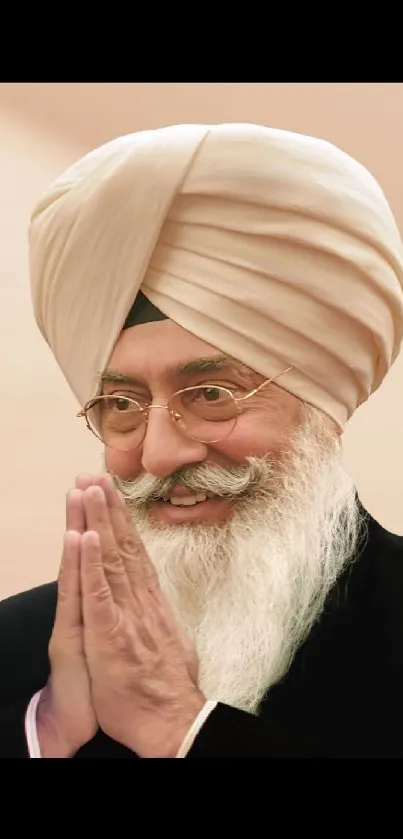 Elderly man with beige turban smiling gently.