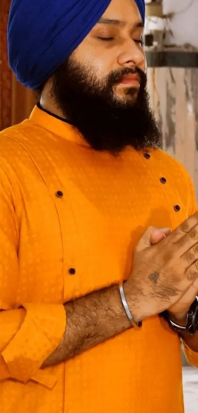 Man meditating in orange attire with blue turban.