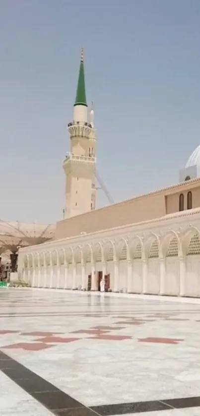 Serene mosque courtyard with blue sky and elegant architecture.