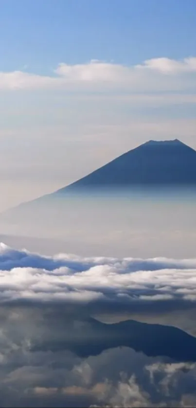 Mountain silhouette above clouds with serene sky.