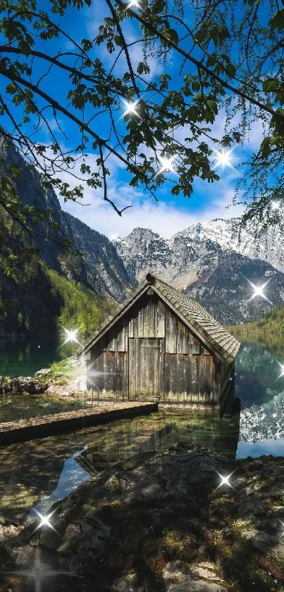 Rustic cabin by mountain lake with snow-capped peaks and clear blue sky.