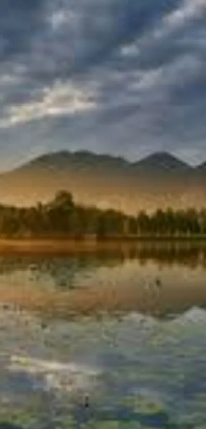 Serene lake at sunset with mountains and a cloudy sky.