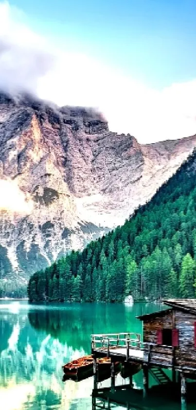 Mountain lake view with cabin, lush greenery, and towering peaks.