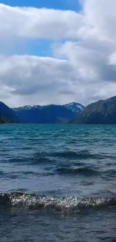 Serene mountain lake with blue waters and cloudy sky.