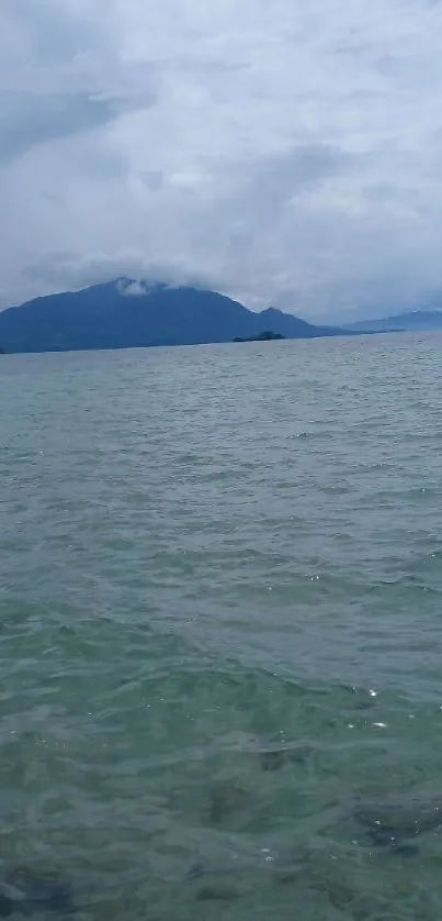 Serene mountain lake view with cloudy sky.