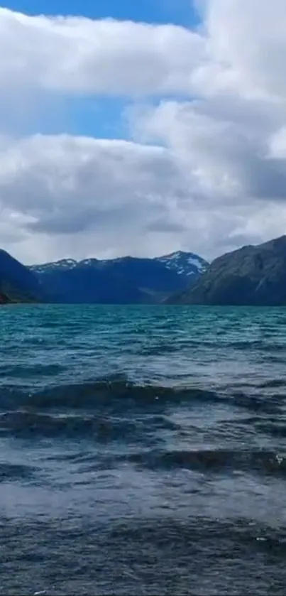 Blue lake with mountains and cloudy sky.