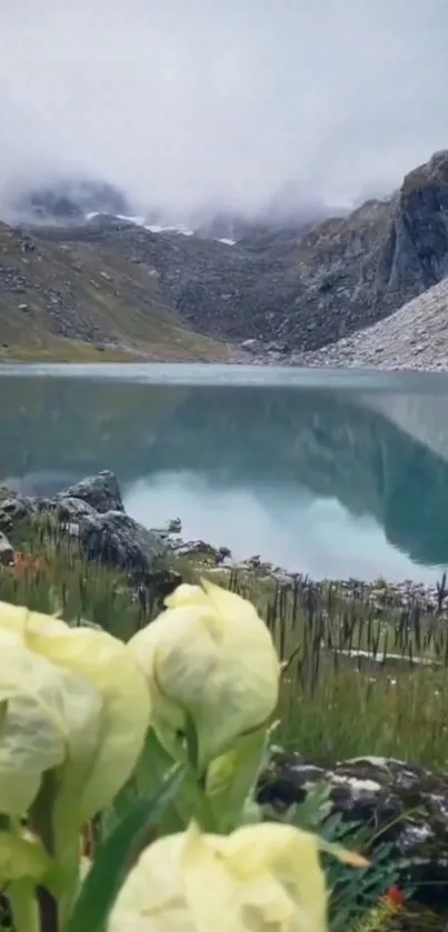 Serene mountain lake with misty peaks and greenery in the foreground.