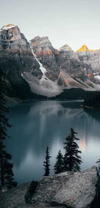 Serene mountain lake view at sunset with turquoise waters and rocky peaks.