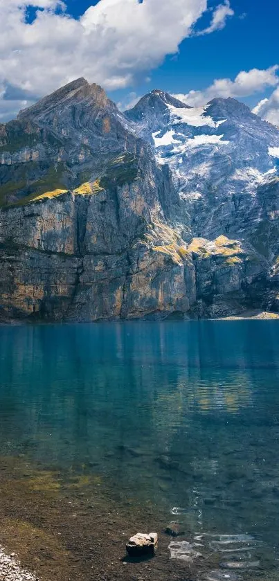 Serene mountain lake with clear blue water and towering rocky peaks under a blue sky.