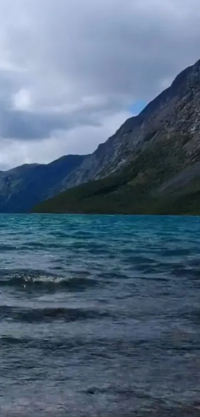 Serene mountain lake with cloudy sky and azure waters.