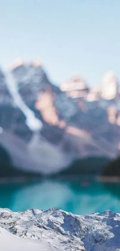 Blurred mountain lake scene with turquoise water and snow-capped peaks.