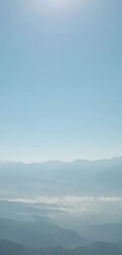 Serene mountain landscape with misty hills and a clear blue sky.