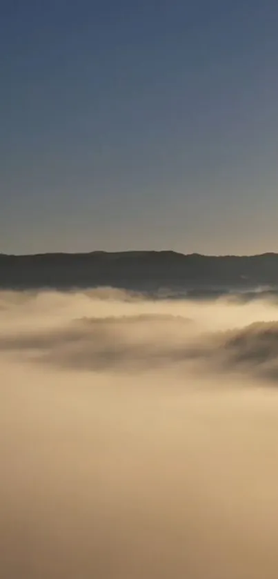 Serene mountain landscape with misty clouds and a clear blue sky.