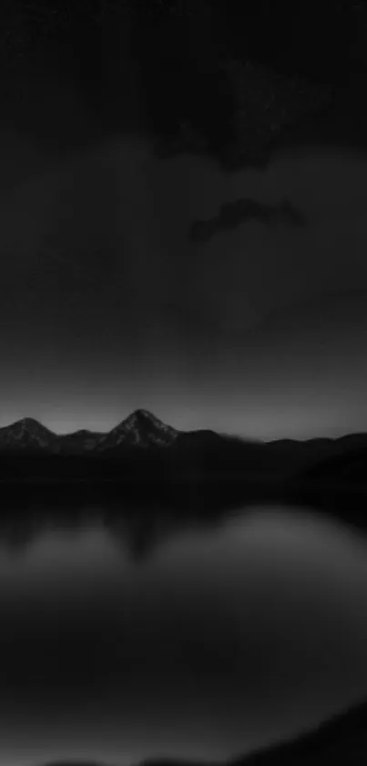 Dark serene mountain nightscape with reflections on a calm lake.