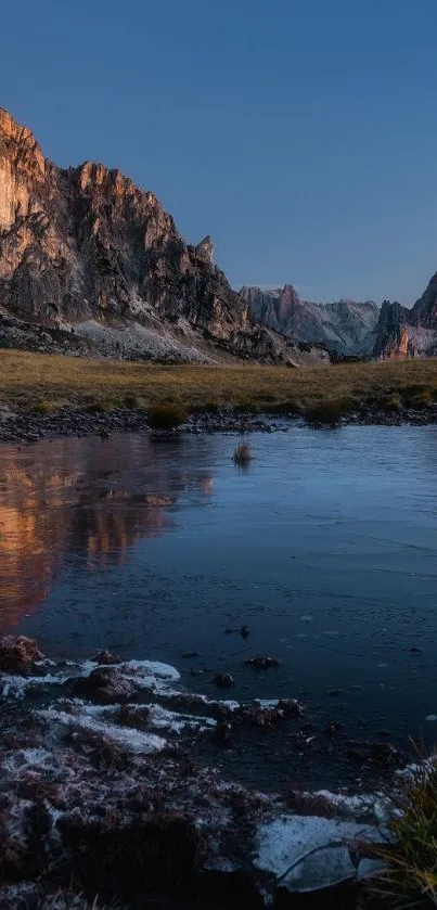 A serene landscape with mountains reflecting in a calm lake under a blue sky.