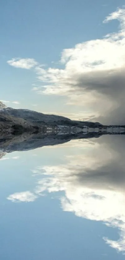 Serene mountain reflection on calm lake with blue sky and clouds.