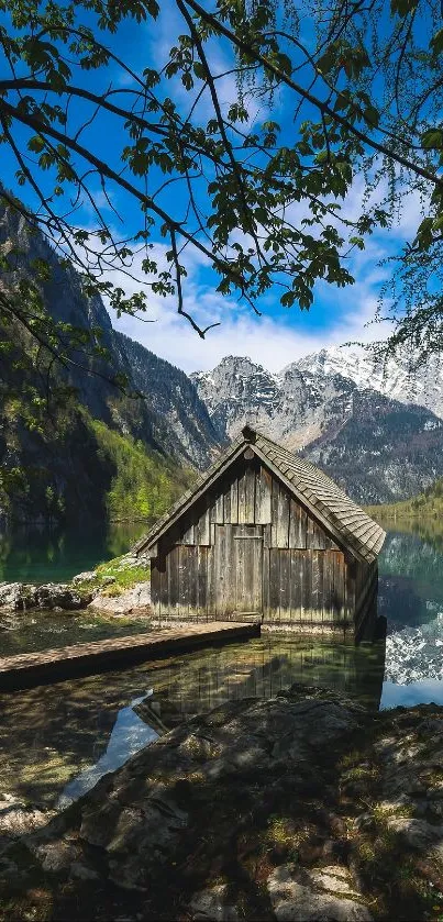 Rustic cabin by a lake with mountain background.