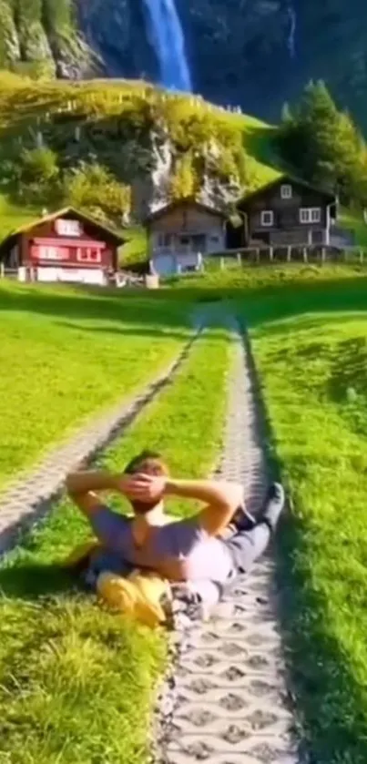 Man relaxing near cabins with waterfall in the background.