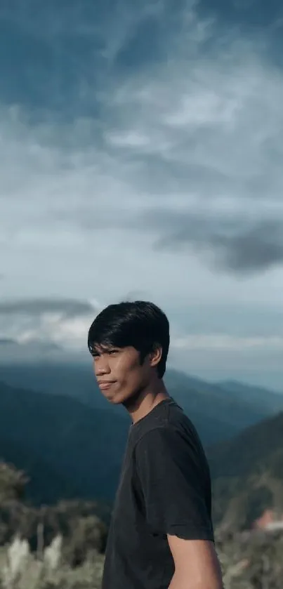 Person in black shirt with mountain and sky background.