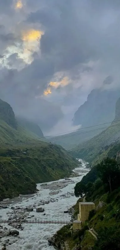 Serene mountain valley with misty clouds and a flowing river.