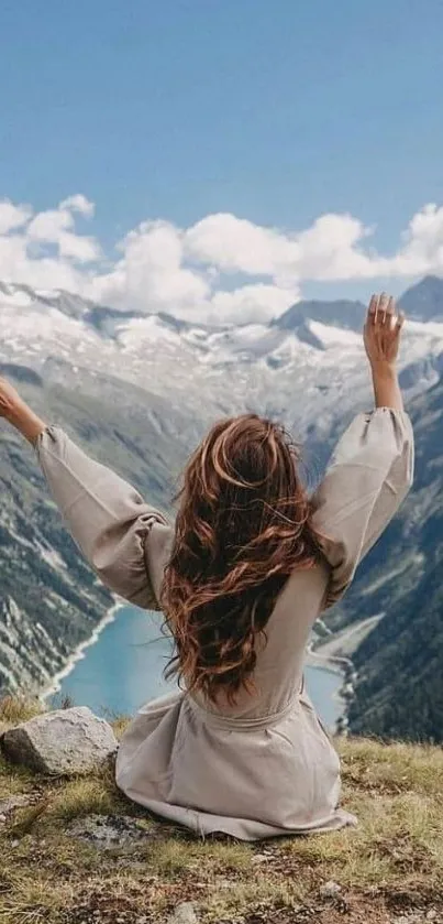 Woman sitting on mountain overlooking serene blue landscape.