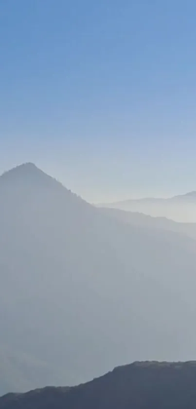 Misty mountains against a serene blue sky.