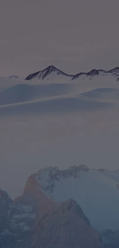 Snow-covered mountains under a pale blue sky.