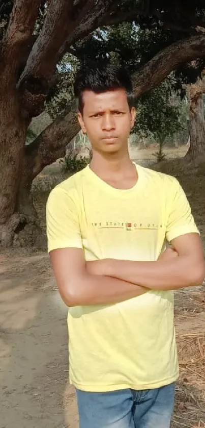 Person in yellow shirt walks through lush, green trees on a sunny day.