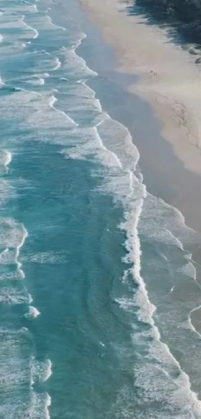 Aerial view of serene ocean beach with blue waves and sandy shore.