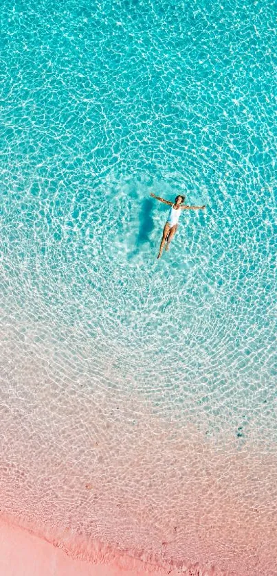 Aerial view of a person in turquoise water near a pink sandy beach.