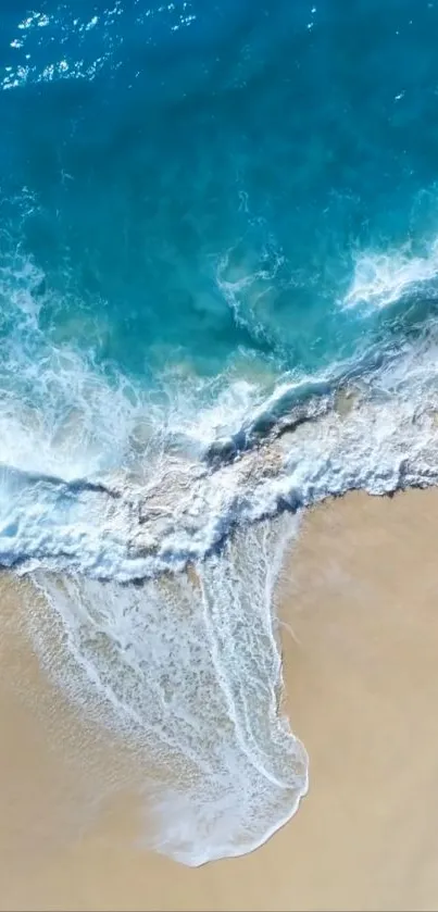 Aerial view of ocean waves meeting sandy beach.