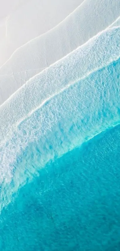 Aerial view of turquoise ocean waves on a white sandy beach.